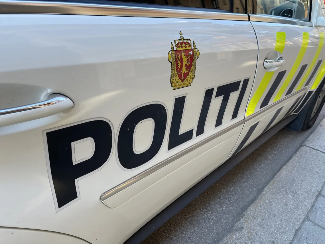 Norwegian police car parked in Norway June 2022: Mercedes-Benz automobile with high-visibility vehicle markings and the coat-of-arms emblem of the Police of Norway.